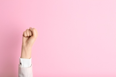 Young woman showing clenched fist on color background. Space for text