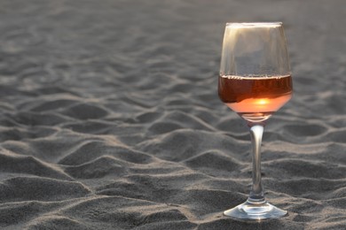 Photo of Glasstasty rose wine on sandy beach, space for text