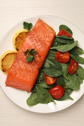 Photo of Tasty grilled salmon with basil, tomatoes and lemon on white wooden table, top view