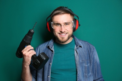 Photo of Young working man with power drill on green background