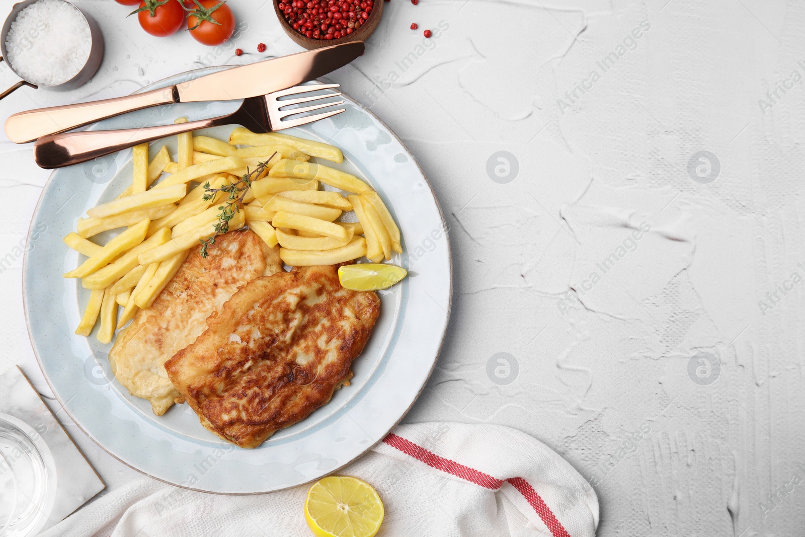 Photo of Tasty soda water battered fish, potato chips and lemon slice served on white textured table, flat lay. Space for text