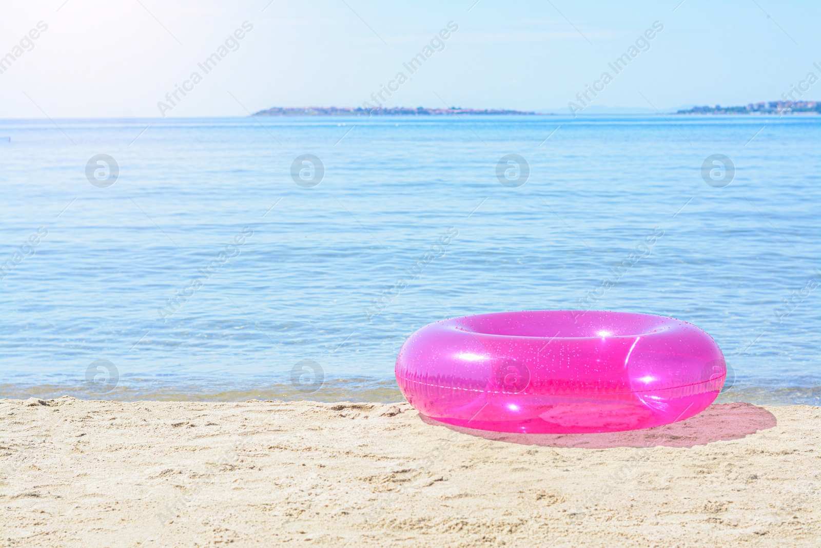 Photo of Bright inflatable ring on sandy beach near sea. Space for text