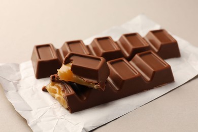 Photo of Tasty sweet chocolate bars with paper wrap on light background