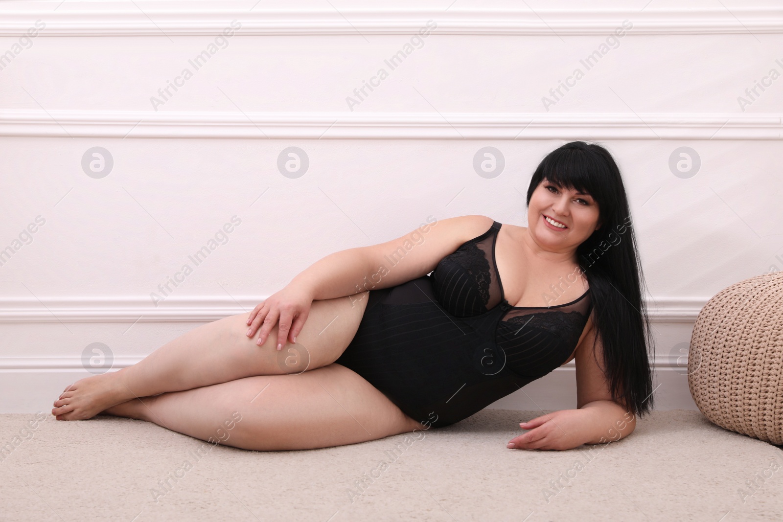 Photo of Beautiful overweight woman in black underwear posing at home. Plus-size model