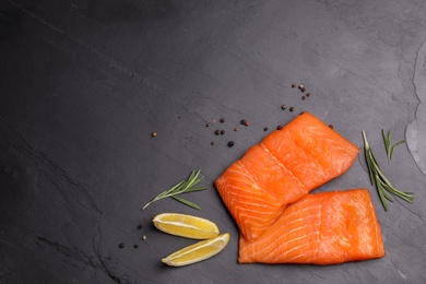 Photo of Tasty salmon fillet on black slate surface, flat lay. Space for text