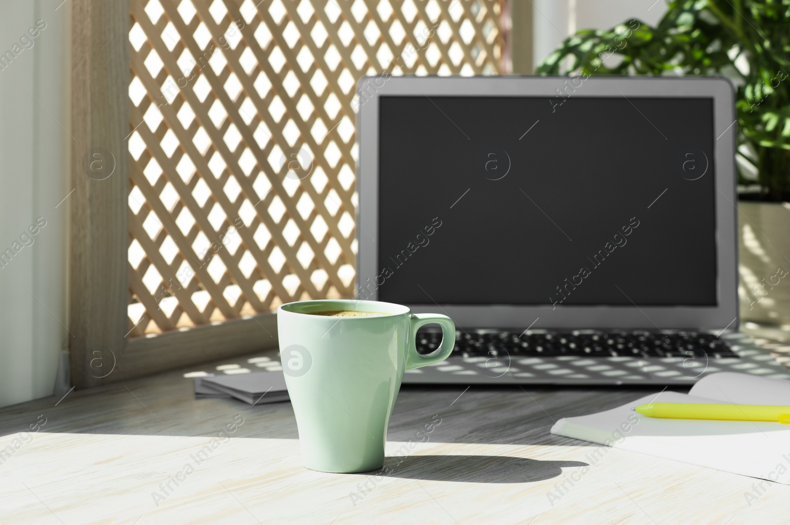 Photo of Cup of coffee, laptop with blank screen, stationery on wooden window sill. Space for text