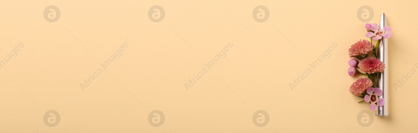 Image of Bullet and beautiful flowers on beige background, flat lay. Banner design with space for text