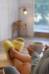 Photo of Woman with cup of aromatic coffee relaxing at home, closeup