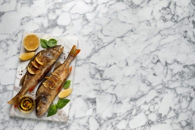 Photo of Tasty homemade roasted perches served on white marble table, top view and space for text. River fish