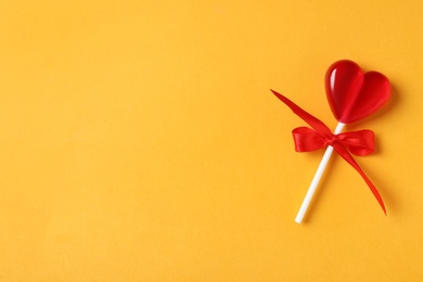 Photo of Sweet heart shaped lollipop on orange background, top view with space for text. Valentine's day celebration