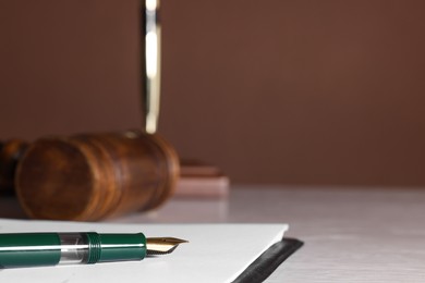 Photo of Fountain pen and paper document on light wooden table, closeup with space for text. Notary service