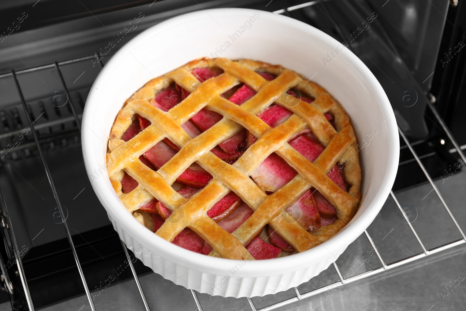 Photo of Baking dish with tasty apple pie in open oven, closeup