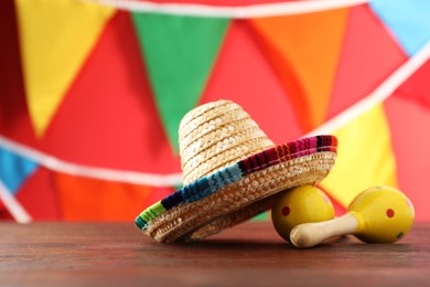 Photo of Mexican sombrero hat and maracas on wooden table . Space for text