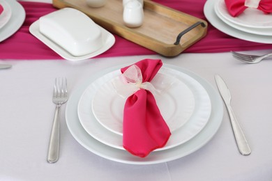 Photo of Color accent table setting. Plates, cutlery and pink napkin, closeup