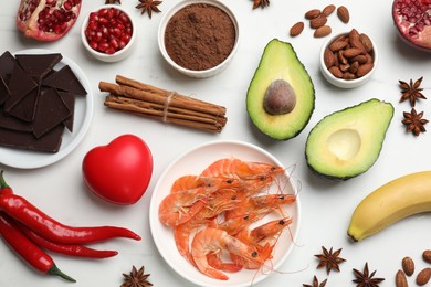 Photo of Natural aphrodisiac. Different food products and red decorative heart on white table, flat lay