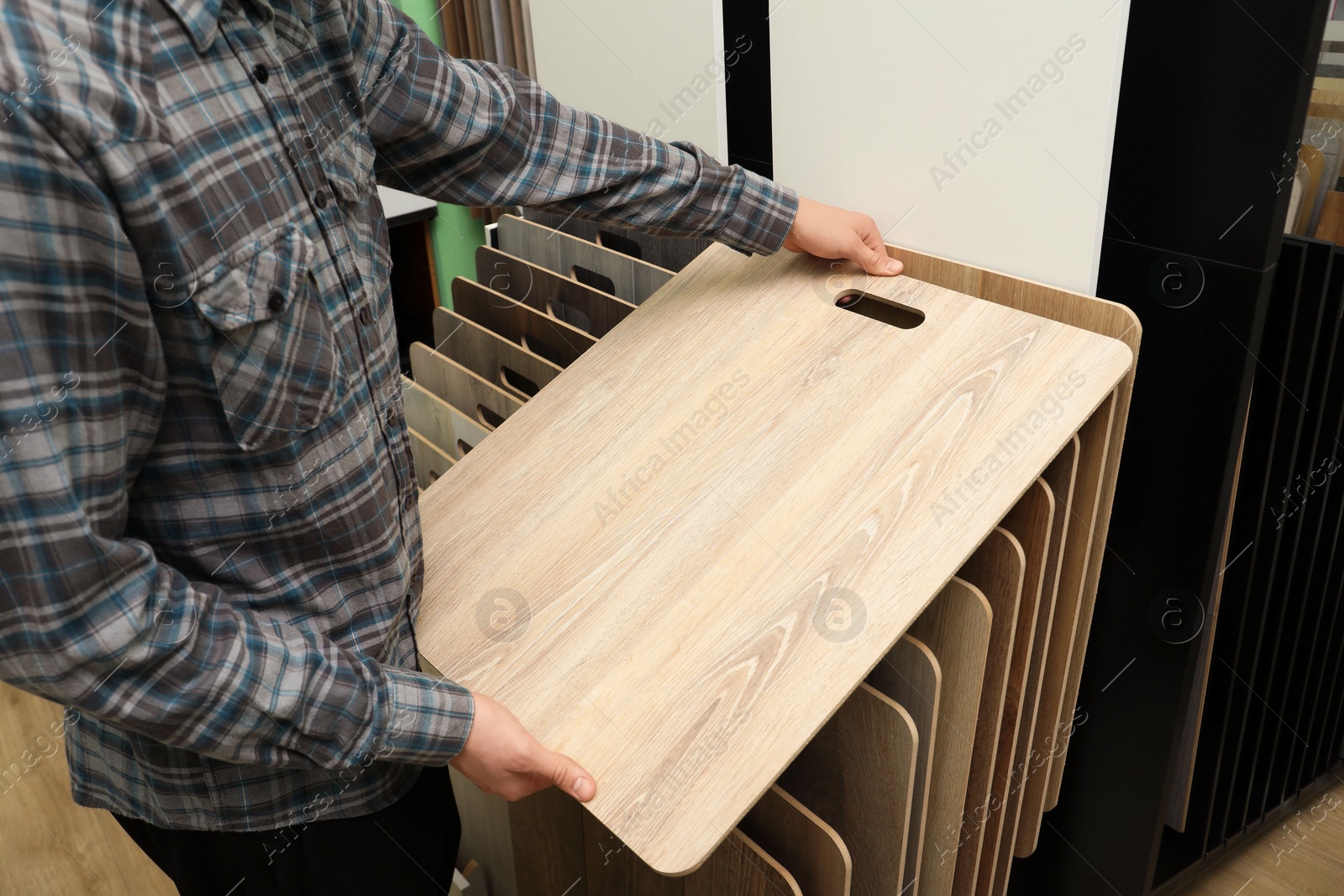 Photo of Man with sample of wooden flooring in shop, closeup