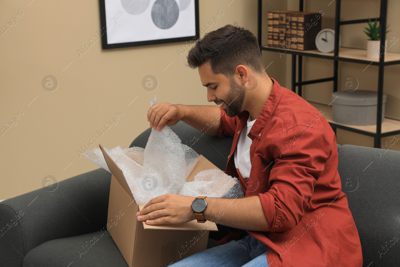 Photo of Man unpacking parcel at home. Online shopping