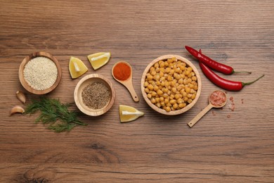 Photo of Delicious chickpeas and different products on wooden table, flat lay. Hummus ingredients