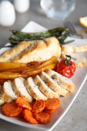 Photo of Tasty cooked chicken fillet and vegetables served on grey table. Healthy meals from air fryer