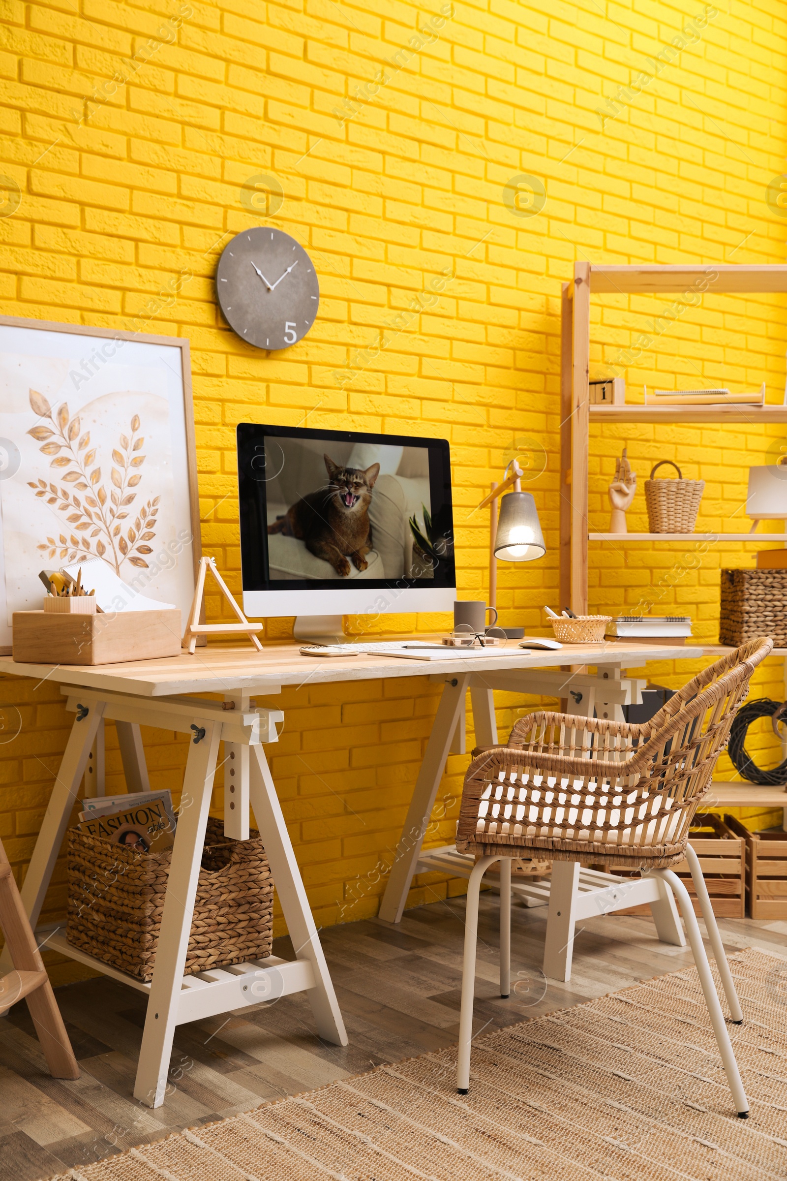 Photo of Stylish home office interior with comfortable workplace near yellow brick wall