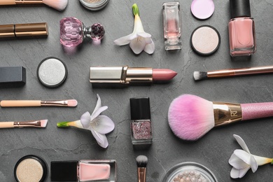 Photo of Many different makeup products and spring flowers on color background, flat lay