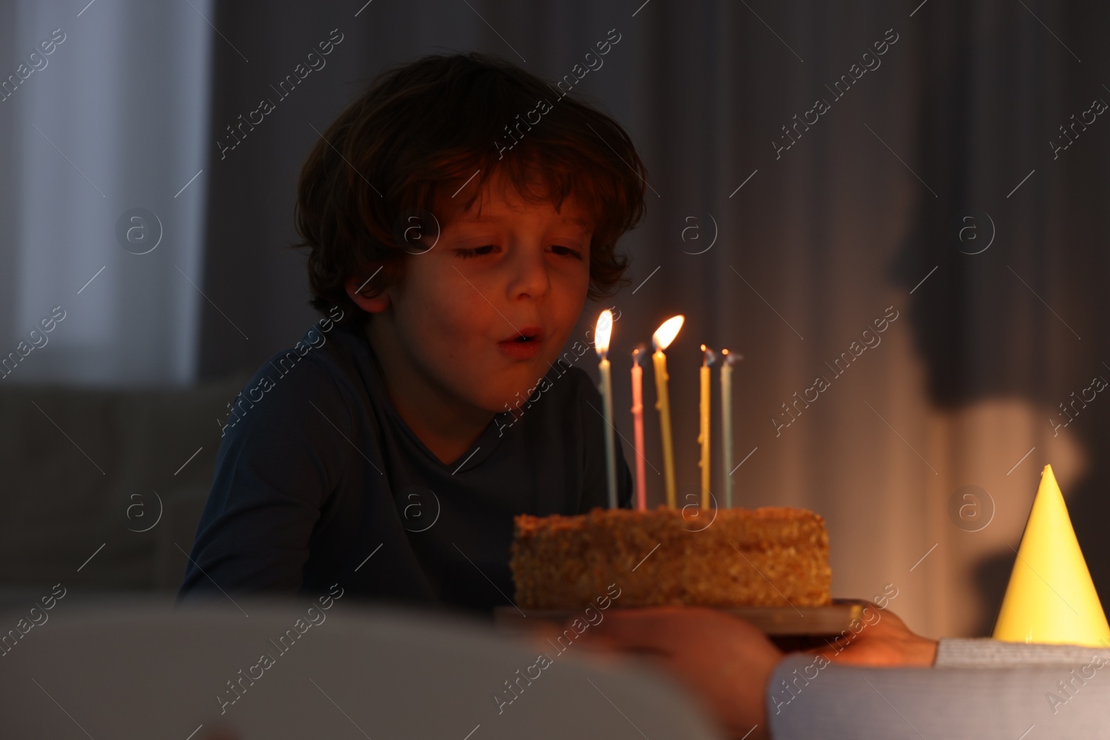 Photo of Birthday celebration. Mother holding tasty cake with burning candles near her son indoors