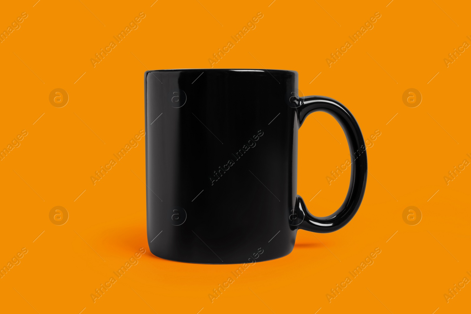 Photo of One black ceramic mug on orange background