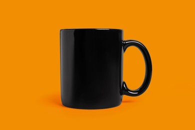 Photo of One black ceramic mug on orange background