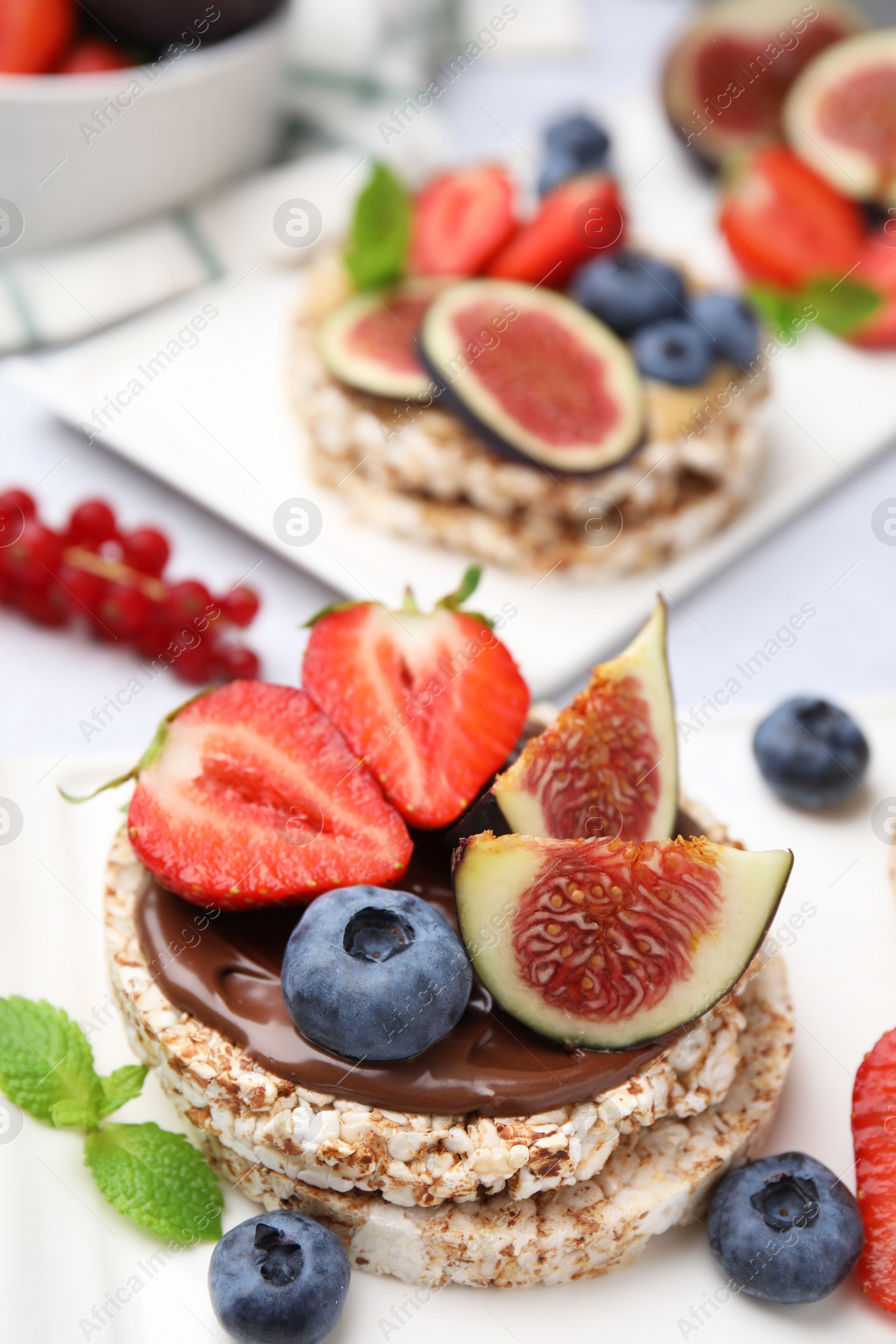 Photo of Tasty crispbreads with chocolate, figs and berries served on light table, closeup