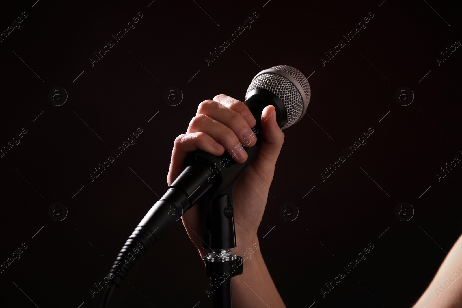 Photo of Woman holding microphone on black background, closeup