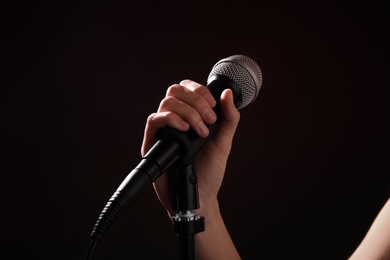 Photo of Woman holding microphone on black background, closeup