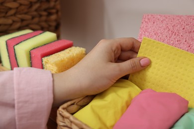 Photo of Woman taking cleaning cloth from basket indoors, closeup view