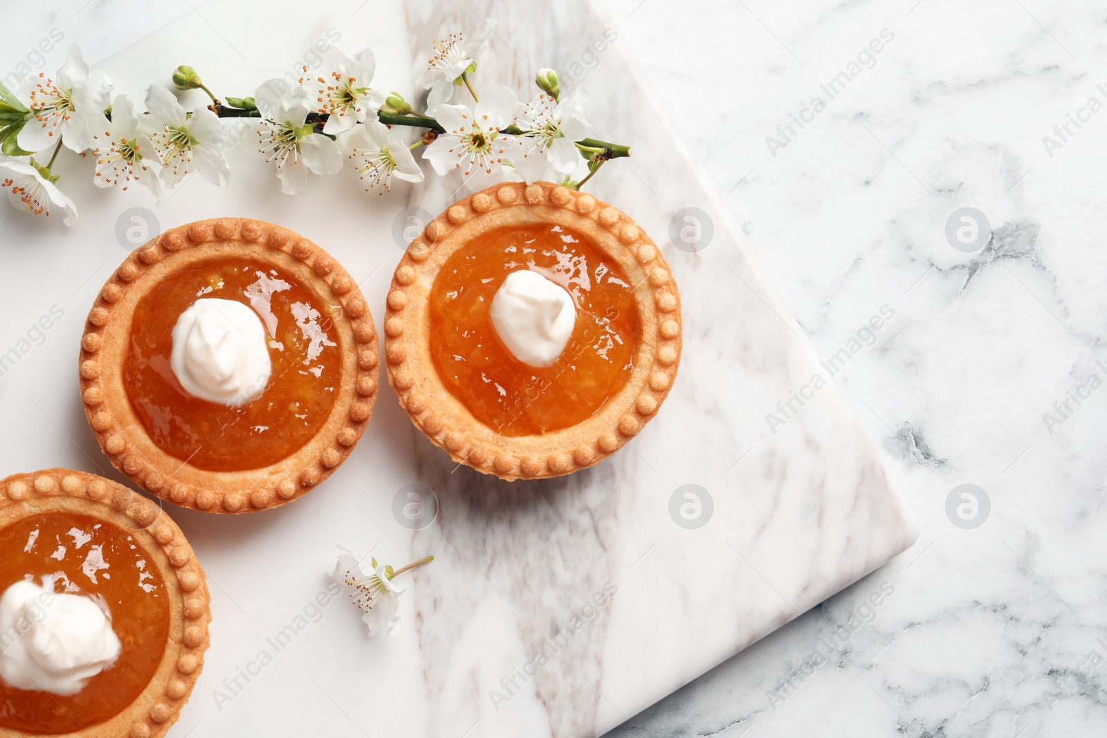 Photo of Tasty tartlets with jam on light background, top view