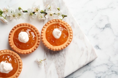 Tasty tartlets with jam on light background, top view