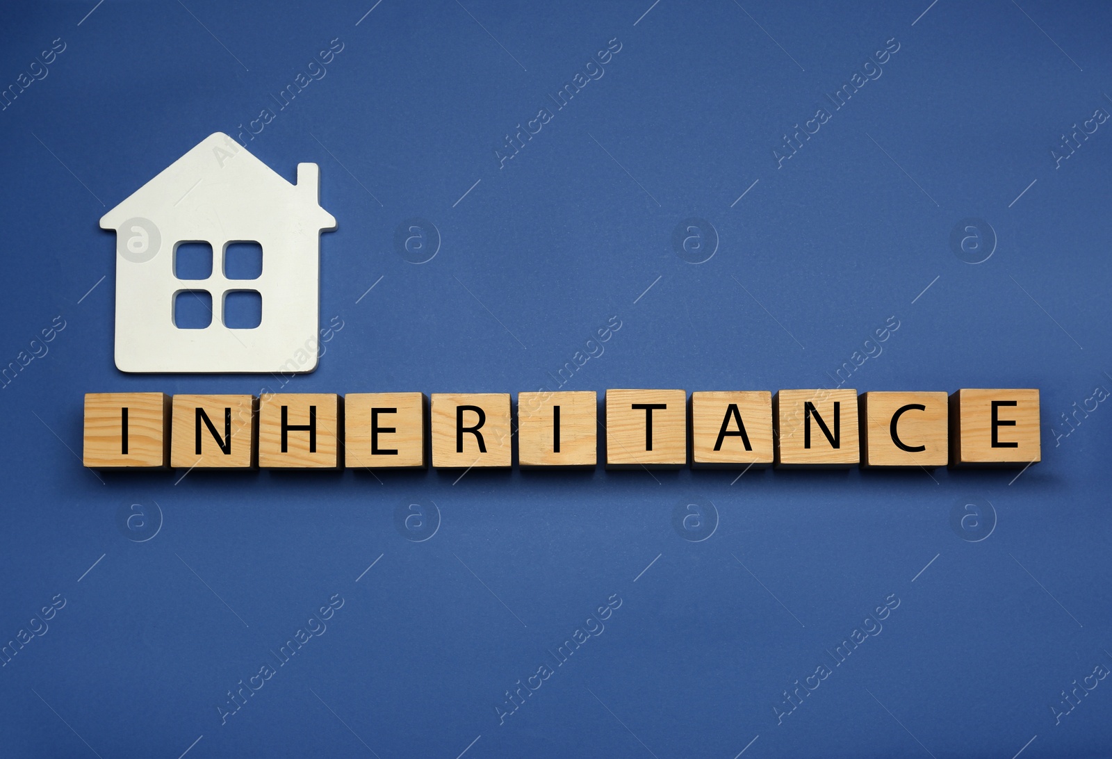 Photo of Word Inheritance made with wooden cubes and house model on blue background, flat lay