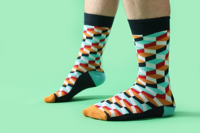 Photo of Man in stylish colorful socks on light green background, closeup