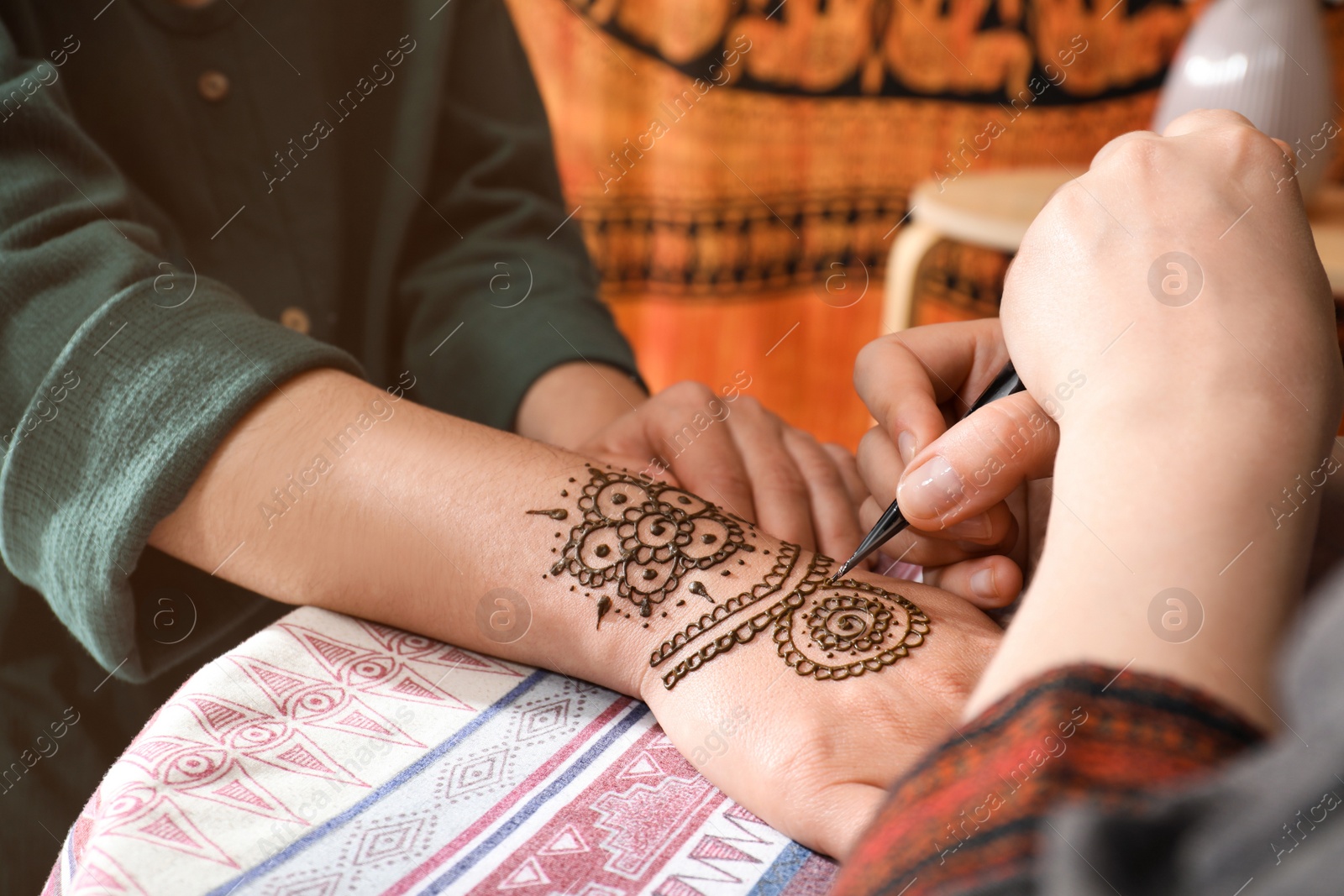 Photo of Master making henna tattoo on hand, closeup. Traditional mehndi