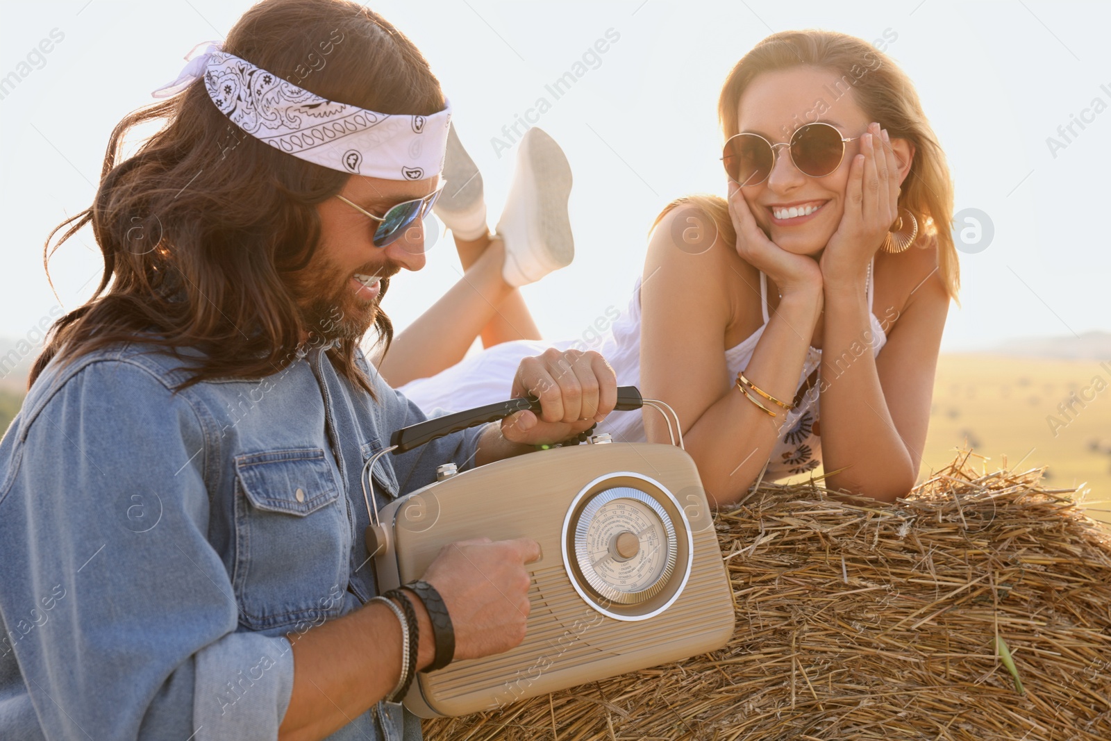 Photo of Happy hippie couple with radio receiver in field