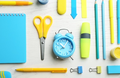 Different bright school stationery on white wooden background, flat lay