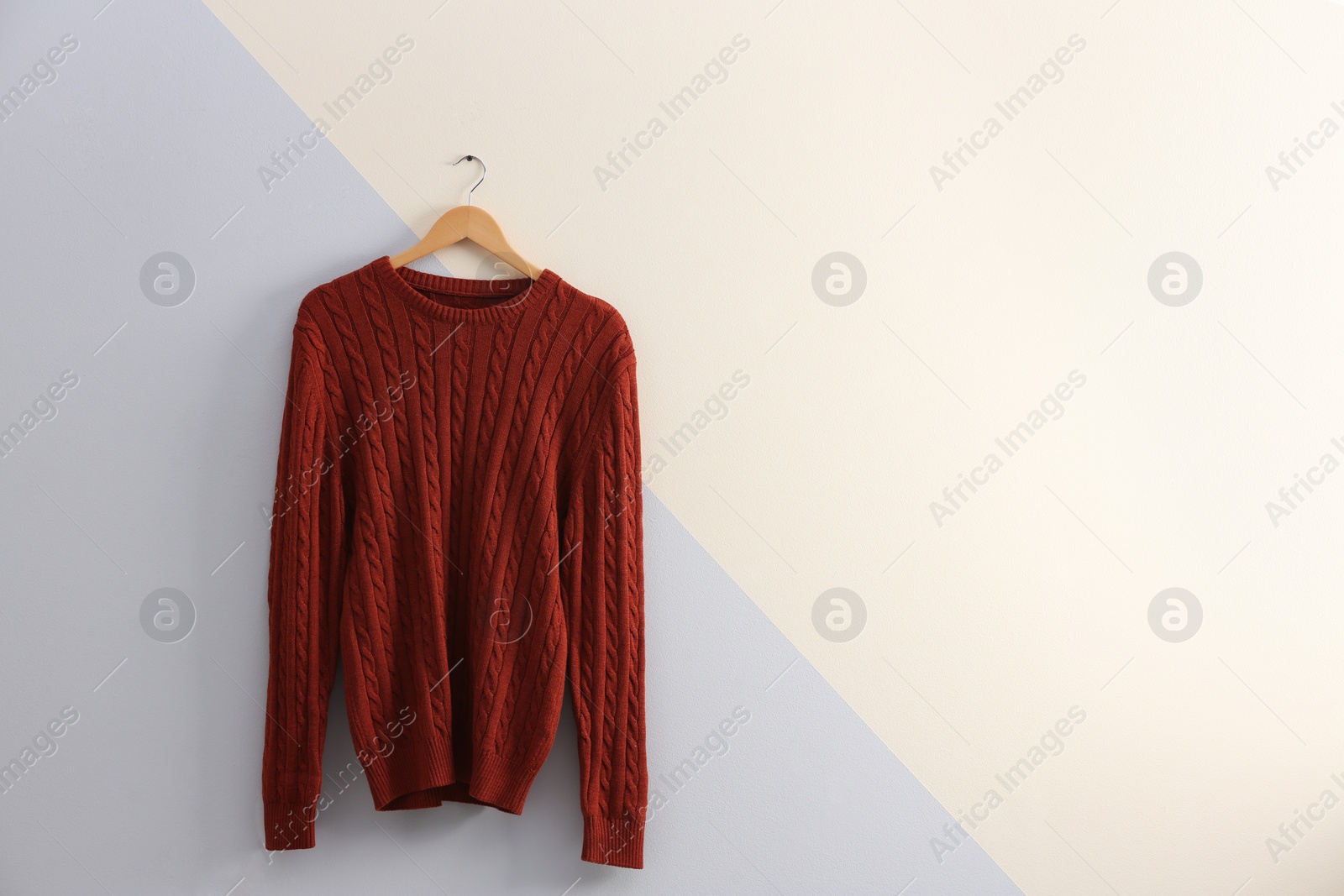 Photo of Hanger with stylish sweater on color wall. Space for text