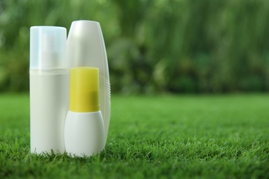Photo of Different insect repellents on green grass. Space for text