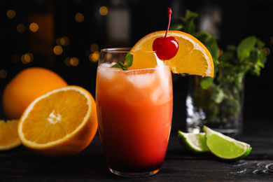 Photo of Fresh alcoholic Tequila Sunrise cocktail on black wooden table