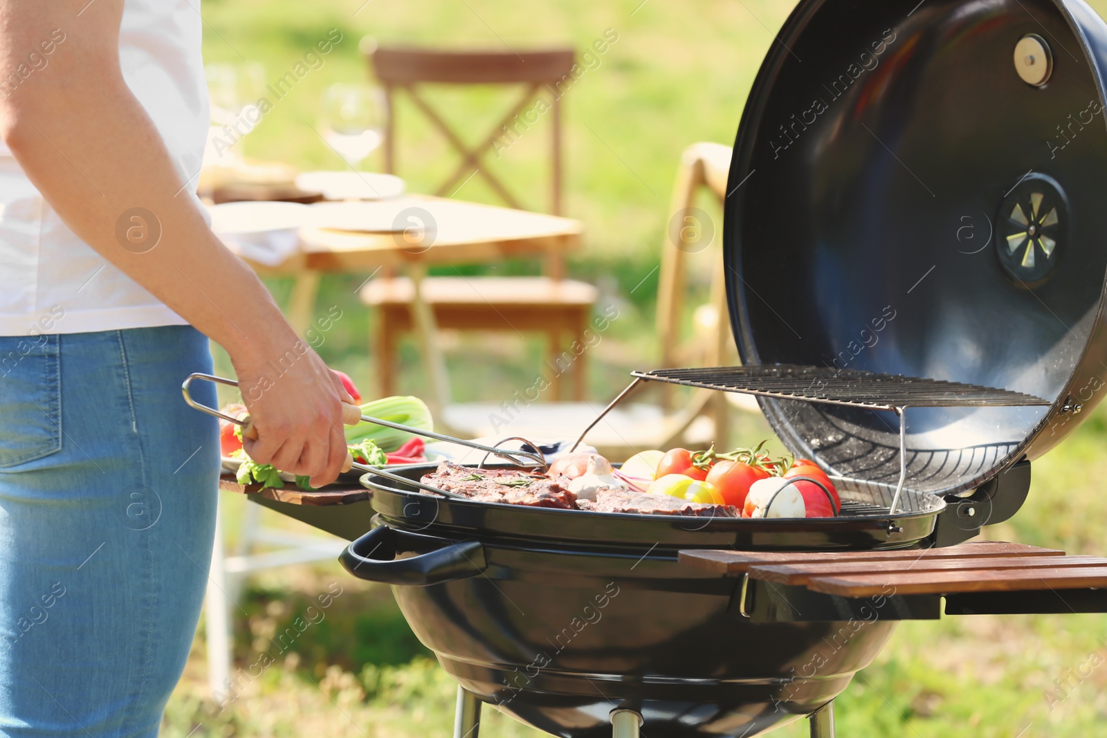 Photo of Man cooking meat and vegetables on barbecue grill outdoors