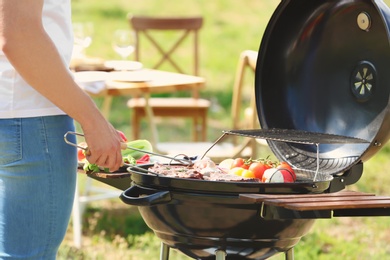 Man cooking meat and vegetables on barbecue grill outdoors