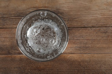 Glass of soda water on wooden table, top view. Space for text