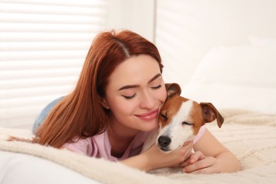 Photo of Woman with her cute Jack Russell Terrier dog on bed at home