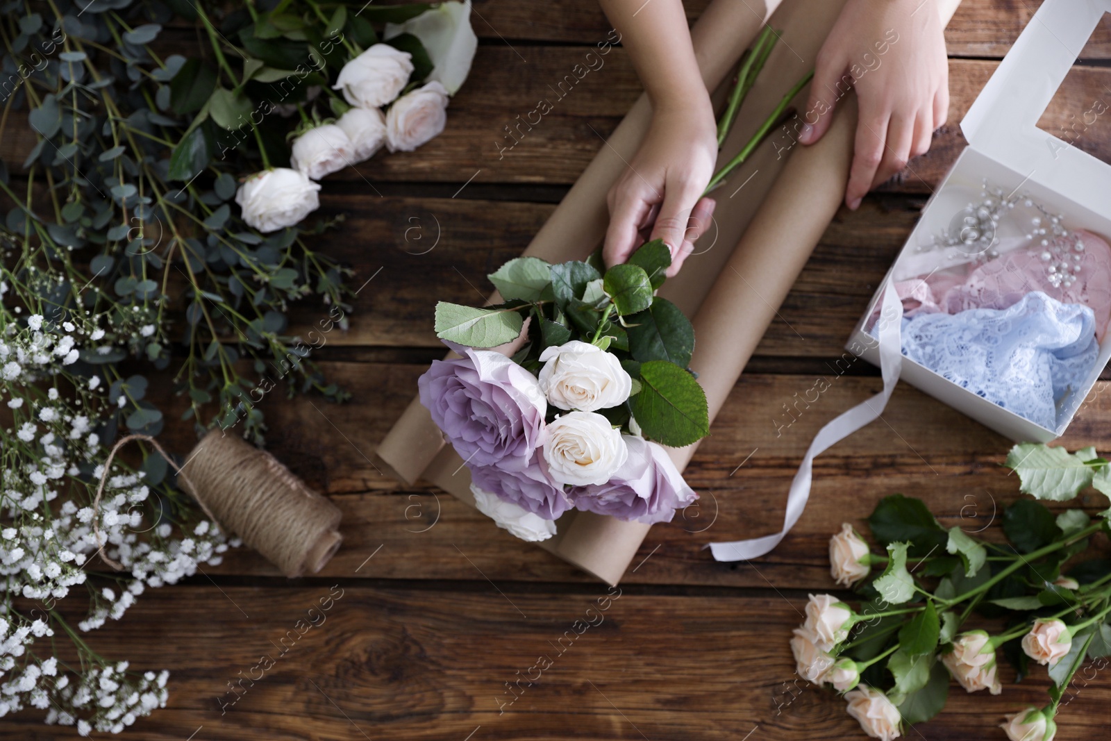 Photo of Florist making beautiful wedding bouquet at wooden table, top view