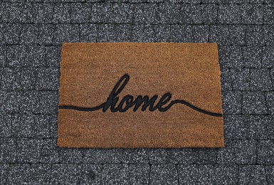 Doormat with word Home on pavement, top view