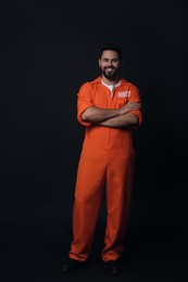 Photo of Happy prisoner in jumpsuit on black background
