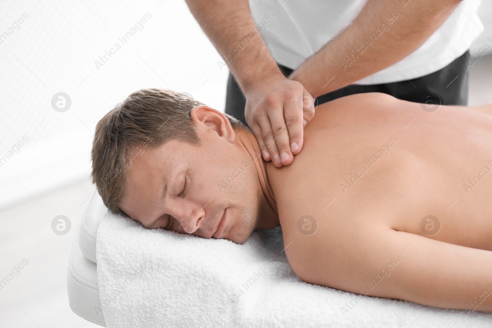 Photo of Relaxed man receiving back massage in wellness center